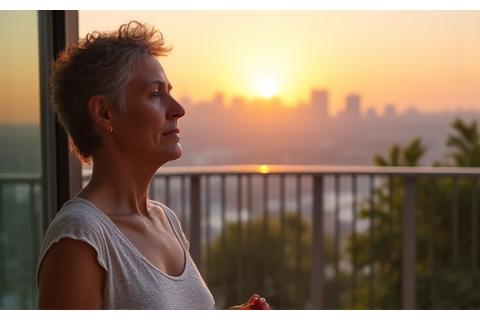 Γυναίκα ηλικίας 40-50 ετών να κάνει διαλογισμό ή βαθιές αναπνοές σε ένα ήρεμο, φυσικό περιβάλλον, με διακριτικά σύμβολα ευεξίας να αιωρούνται, υποδηλώνοντας διαχείριση άγχους.