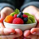 Άτομο εστιάζει σε ένα μπολ με φρούτα, επιδεικνύοντας ενσυνείδητη διατροφή.